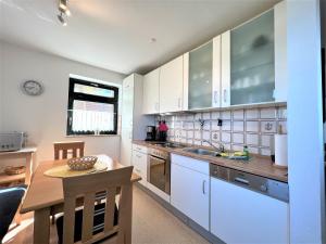 a kitchen with white cabinets and a wooden table at Haus Strandkieker, An der Rennweide 12c, 65qm in Dangast