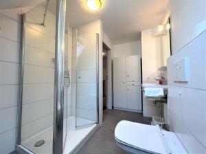 a bathroom with a toilet and a glass shower at Haus Strandkieker, An der Rennweide 12c, 65qm in Dangast +16 photos