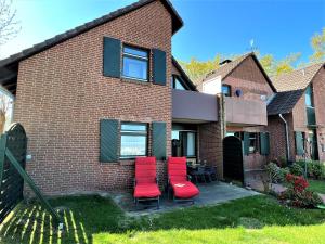 a brick house with red chairs and a table at Haus Strandkieker, An der Rennweide 12c, 65qm in Dangast