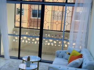 Cherry home في مومباسا: غرفة معيشة مع أريكة زرقاء ونافذة