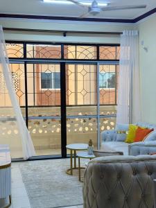 uma sala de estar com um sofá e uma grande janela em Cherry home em Mombaça