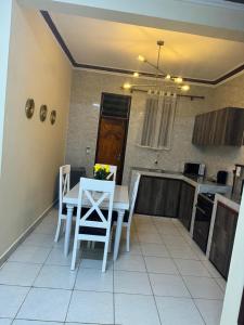 Cherry home في مومباسا: مطبخ مع طاولة بيضاء وكراسي في غرفة