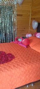 a bed with an orange blanket with a toy on it at CABAÑA ALTO DE LUNA 1 in La Vega