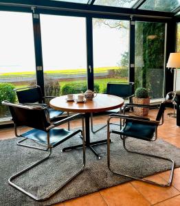 einen Tisch und Stühle in einem Zimmer mit Fenstern in der Unterkunft Haus Meeresblick EG An der Rennweide 18, 100qm in Dangast