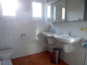 ein Badezimmer mit zwei Waschbecken, einem WC und einem Spiegel in der Unterkunft Haus Meeresblick EG An der Rennweide 18, 100qm in Dangast