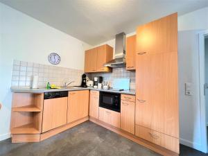 a kitchen with wooden cabinets and a clock on the wall at Apartmenthaus am Nordseestrand Whg 7, An der Rennweide 1B, 70qm in Dangast