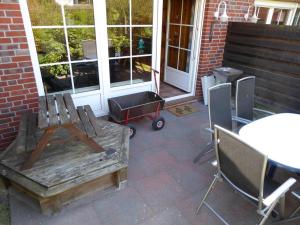 un patio avec une table et un chariot et une table et des chaises dans l'établissement Haus Seemöwe Hollwert 33d 90qm, à Dangast