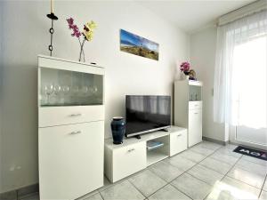 ein Wohnzimmer mit einem TV und weißen Schränken in der Unterkunft Haus Waldesblick An der Rennweide 26a 75 qm in Dangast