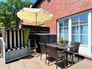 ein Tisch und Stühle mit einem Sonnenschirm auf einer Terrasse in der Unterkunft Haus Waldesblick An der Rennweide 26a 75 qm in Dangast