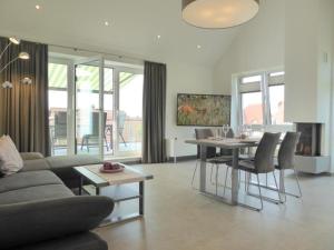 uma sala de estar com um sofá, uma mesa e cadeiras em Premium-Penthouse Oceans Eleven, Am Alten Deich 14 11 em Dangast