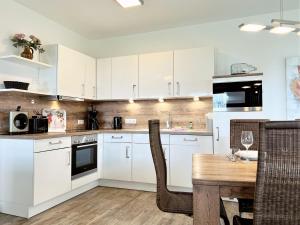 Una cocina con gabinetes blancos y una mesa de madera. en Apartment Buddelschiff, Am Alten Deich 18 3, en Dangast