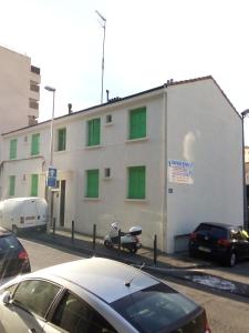 een wit gebouw met groene ramen en een scooter voor de deur bij Bienvenus ! Appartement jaune in Marseille