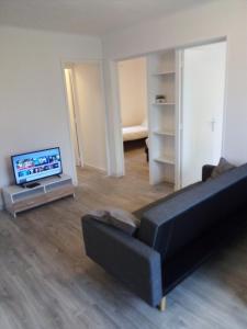 een woonkamer met een zwarte bank en een televisie bij Bienvenus ! Appartement jaune in Marseille