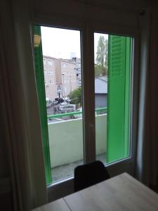 een kamer met een raam met groene luiken en een tafel bij Bienvenus ! Appartement jaune in Marseille
