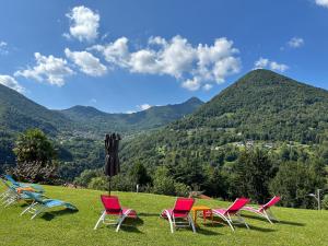 4 sillas y un paraguas en un campo con montañas en Villa Oleandra nearby Argegno with privet Garden & Pool, en Dizzasco