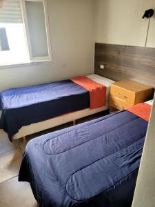 a bedroom with three beds with blue and orange sheets at Hotel Canciller in Mar del Plata