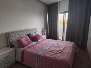 Un dormitorio con una cama con almohadas rosas y una ventana en Isa Charme Home, en Praia