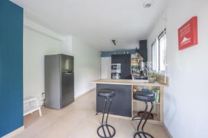 a kitchen with two stools and a counter with a refrigerator at La 745 Summer Holiday home near the sea in Commes