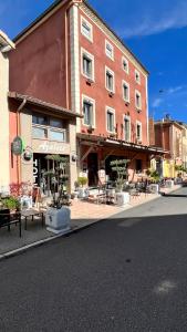 un gran edificio de ladrillo con mesas y sillas en una calle en Logis Hôtel Restaurant Azalées en Tournon-sur-Rhône