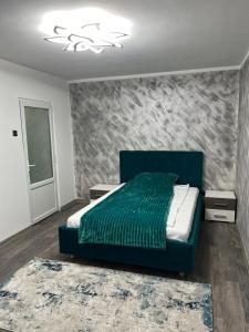 a bedroom with a blue bed in a room at Green Apartament in Târgu Jiu