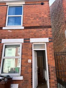 a brick house with a white door and two windows at Nice 2Bedroom house for Family in Nottingham
