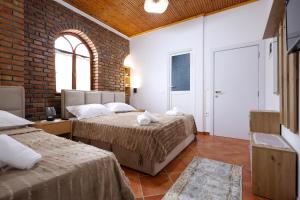a bedroom with two beds and a brick wall at Hotel Boutique BUZI in Berat