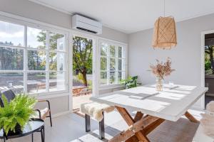 a dining room with a white table and windows at Saunamaki Resort Guesthouse - Countryside Views in Salo