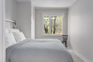 a white bedroom with a bed and a window at Saunamaki Resort Guesthouse - Countryside Views in Salo