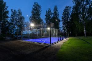 a glass house with a tennis court at night at Saunamäki - Hilda in Salo