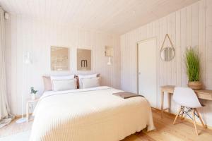 a white bedroom with a large bed and a chair at Stay North - Villa Katajala in Hämeenlinna