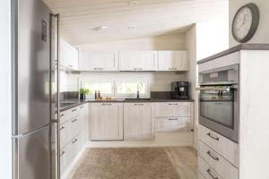 a kitchen with white cabinets and a clock on the wall at Stay North - Villa Kalksved in Sipoo