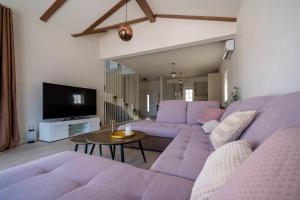 a living room with purple couches and a tv at Villa Bohemica with Private Heated Pool in Orebić