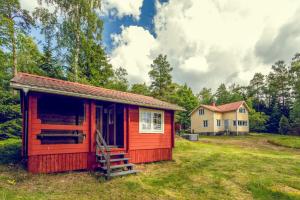 una cabaña roja en un patio con una casa en el fondo en Villa Porkkala - Seafront Jacuzzi Nature Reserve en Kirkkonummi
