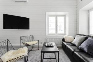 een woonkamer met een bank en een tv aan de muur bij Charming Riverside House with Terrace in Turku