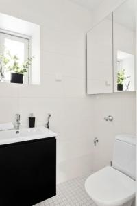 a white bathroom with a toilet and a sink at Charming Riverside House with Terrace in Turku