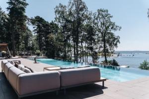 un sofá sentado en un patio junto a una piscina en Stay North - Villa Lovo - Perfect Island Retreat, en Espoo