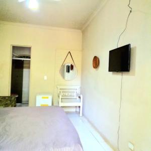 um quarto com uma cama e uma televisão na parede em Residencial Praia Bertioga - Pé na Areia em Bertioga