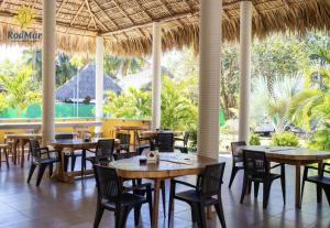 un restaurante con mesas, sillas y palmeras en RodMar Hotel, en El Cuco