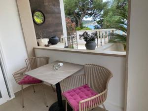 a table and chairs with pink cushions on a balcony at Beach Apartments Ankora in Makarska