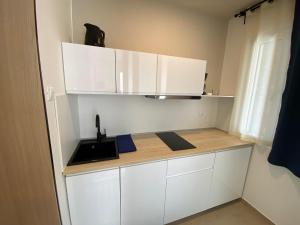 una pequeña cocina con armarios blancos y fregadero en Beach Apartments Ankora, en Makarska