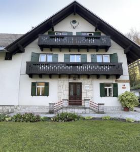 Cette maison blanche dispose de volets verts et d'un balcon. dans l'établissement Apartments Škantar, à Bohinj