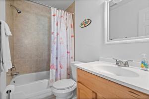 a bathroom with a sink and a toilet and a shower curtain at Schooner by the Sea -- Beach and History await in Saint Augustine Beach