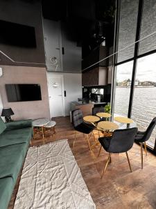 ein Wohnzimmer mit Tischen und Stühlen sowie eine Küche in der Unterkunft Houseboat EnergyApart in Stettin