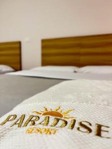 a sign on a bed in a hotel room at Paradise Resort in Los Santos