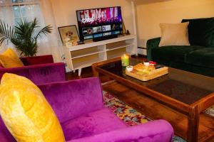 a living room with purple couches and a tv at Long Mountain Suite W/Hot tub in Amherst