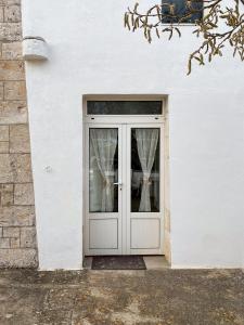 une porte menant à une maison blanche avec des rideaux dans l'établissement Trullo Pinto, à Locorotondo