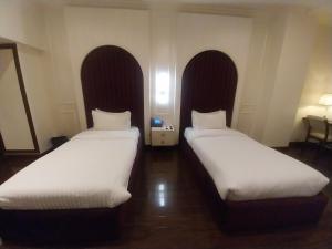 two beds in a room with white sheets at Hotel MERIDIAN in Kary