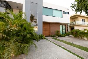 een huis met palmbomen ervoor bij Casa 4 recamaras, alberca, terraza y club playa. in Cruz de Huanacaxtle