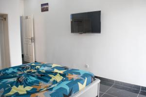 Schlafzimmer mit einem Bett und einem TV an der Wand in der Unterkunft Studio moderne avec Balcon in Pointe-Noire