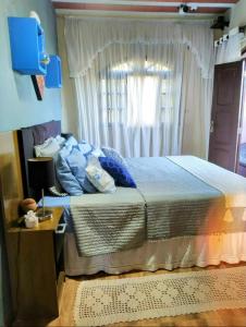 a bedroom with a bed with blue pillows and a window at Casa de campo Domeni rustica e próximo a cidade de Juiz de Fora MG in Juiz de Fora